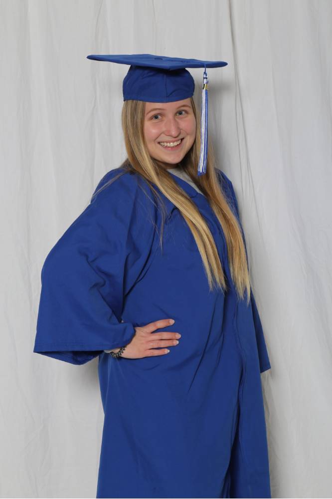 single girl poses in cap and gown blue